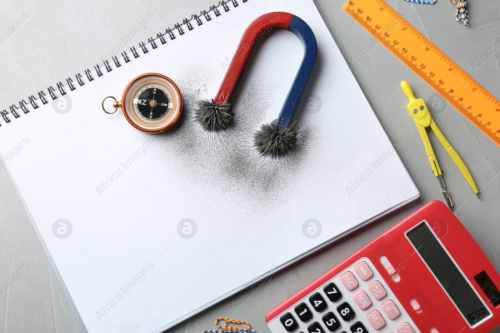 Photo of Notebook, compass and magnet with iron powder on table, flat lay composition. Space for text