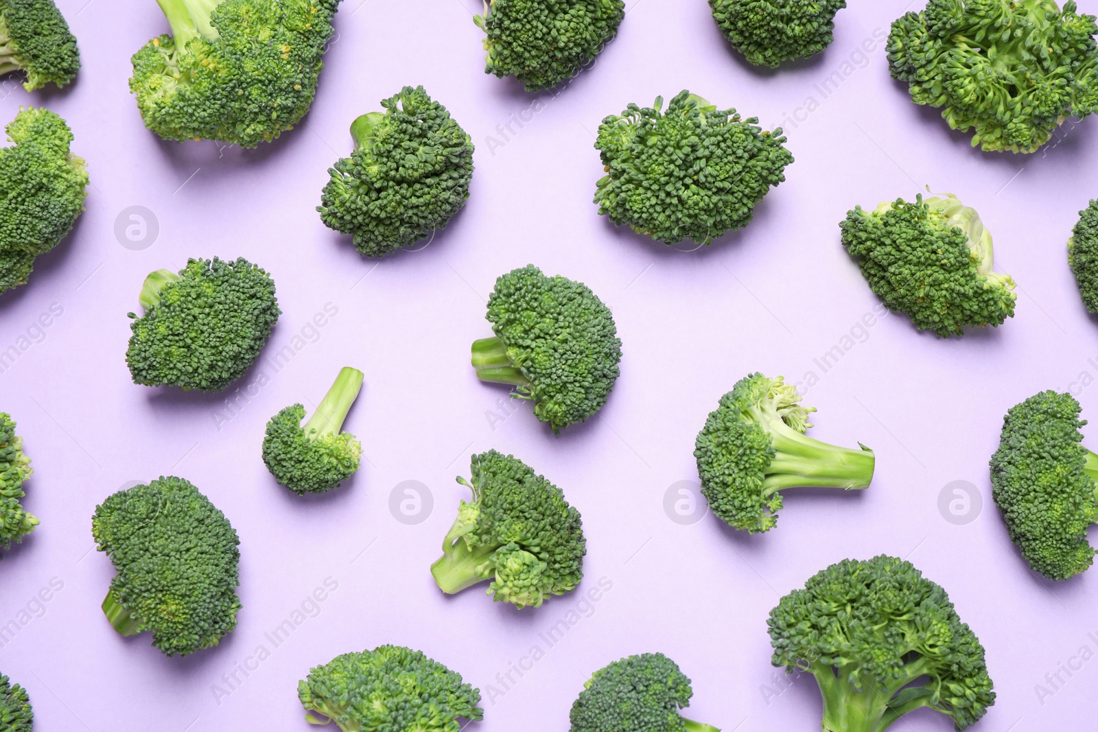 Photo of Fresh tasty broccoli on violet background, flat lay