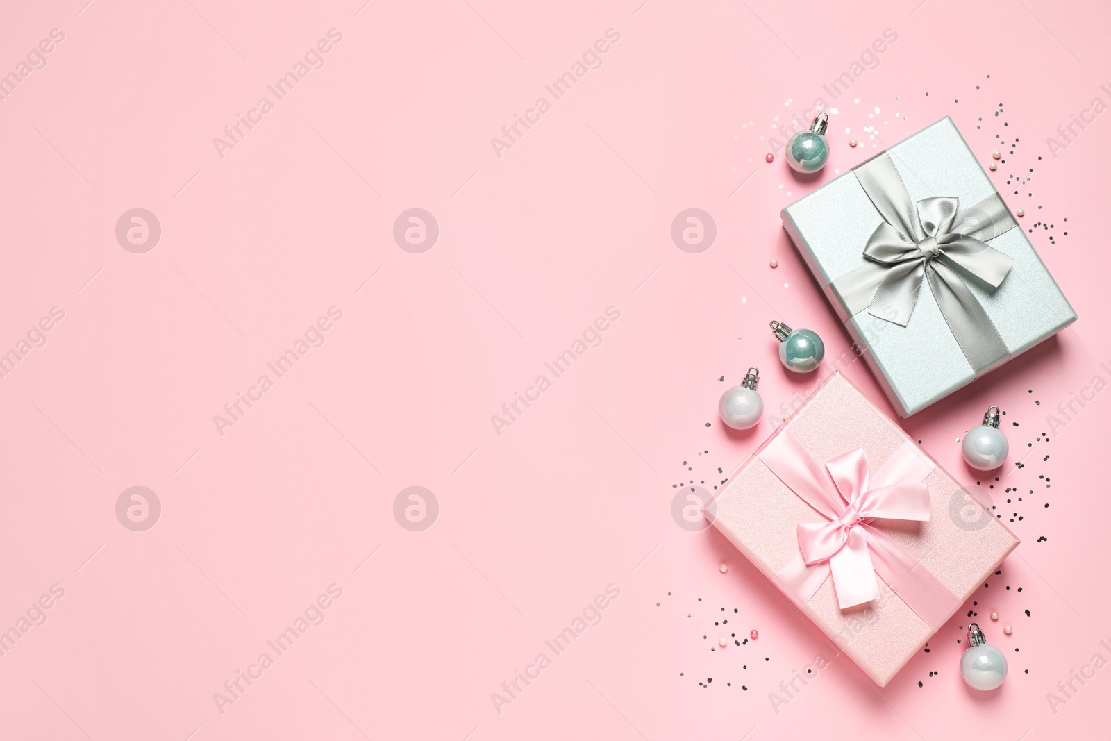 Photo of Beautiful gift boxes, Christmas balls and confetti on pink background, flat lay. Space for text