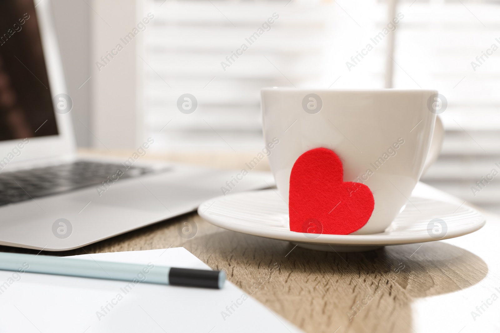 Photo of Cup with red heart on table, space for text. Valentine's day celebration