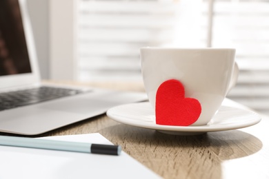 Photo of Cup with red heart on table, space for text. Valentine's day celebration