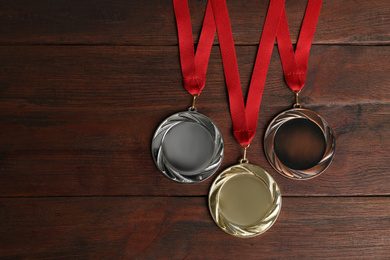 Gold, silver and bronze medals on wooden background, flat lay. Space for design