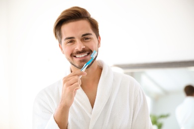 Photo of Portrait of young man with toothbrush in bathroom. Personal hygiene