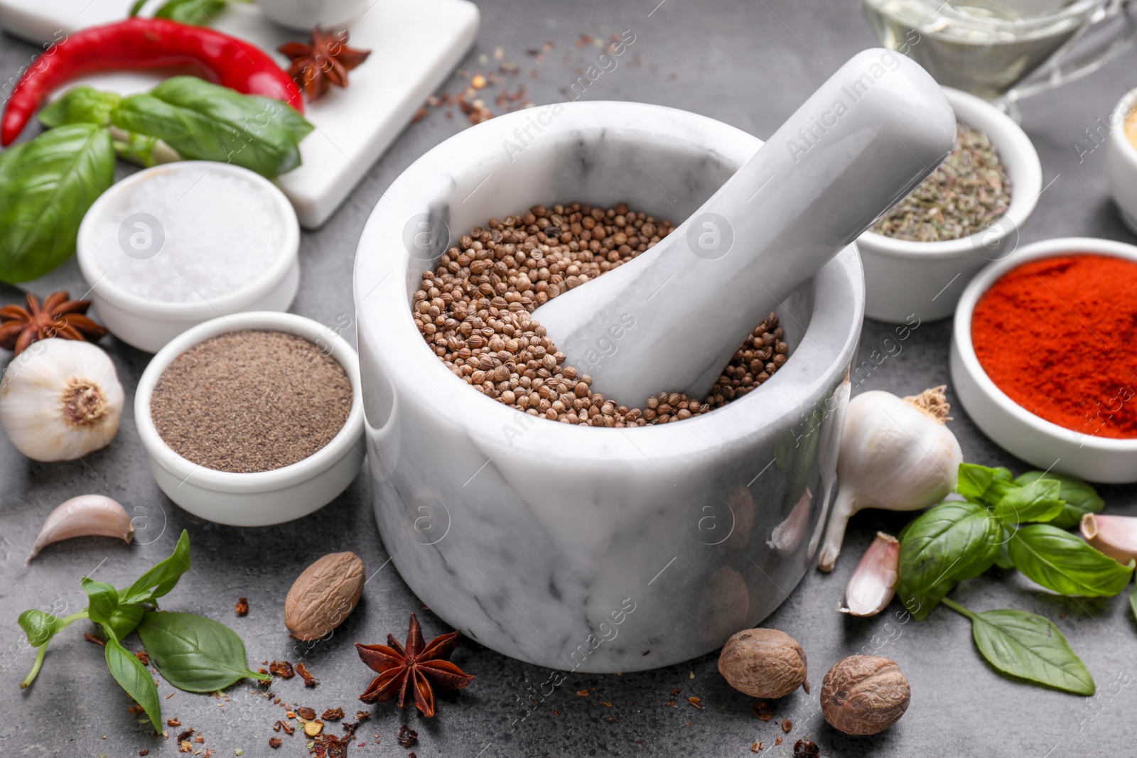 Photo of Mortar with different spices on grey table, closeup