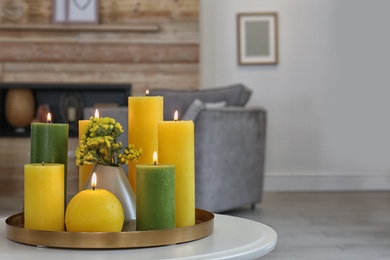 Photo of Tray with burning candles on table in living room