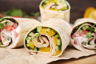Photo of Delicious sandwich wraps with fresh vegetables on wooden board, closeup