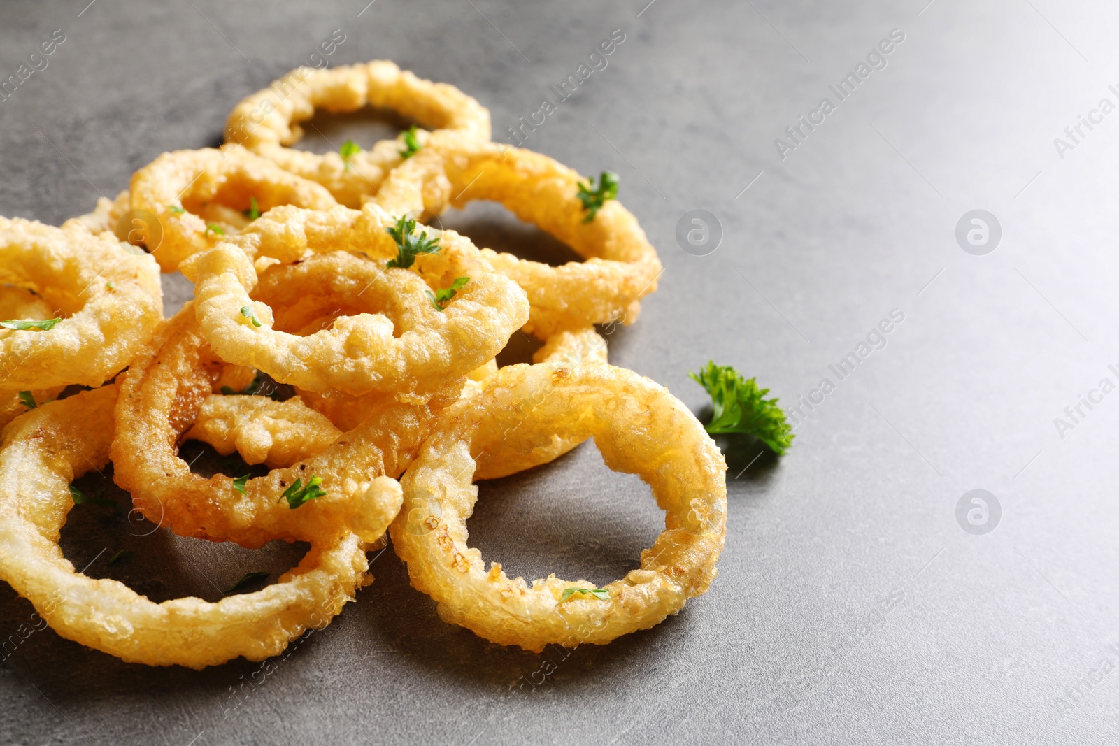 Photo of Homemade crunchy fried onion rings on color table, closeup. Space for text