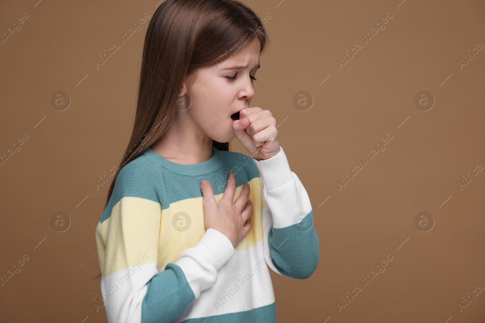 Photo of Sick girl coughing on brown background. Cold symptoms