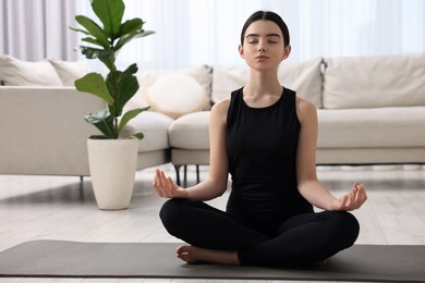 Photo of Beautiful girl meditating on yoga mat at home