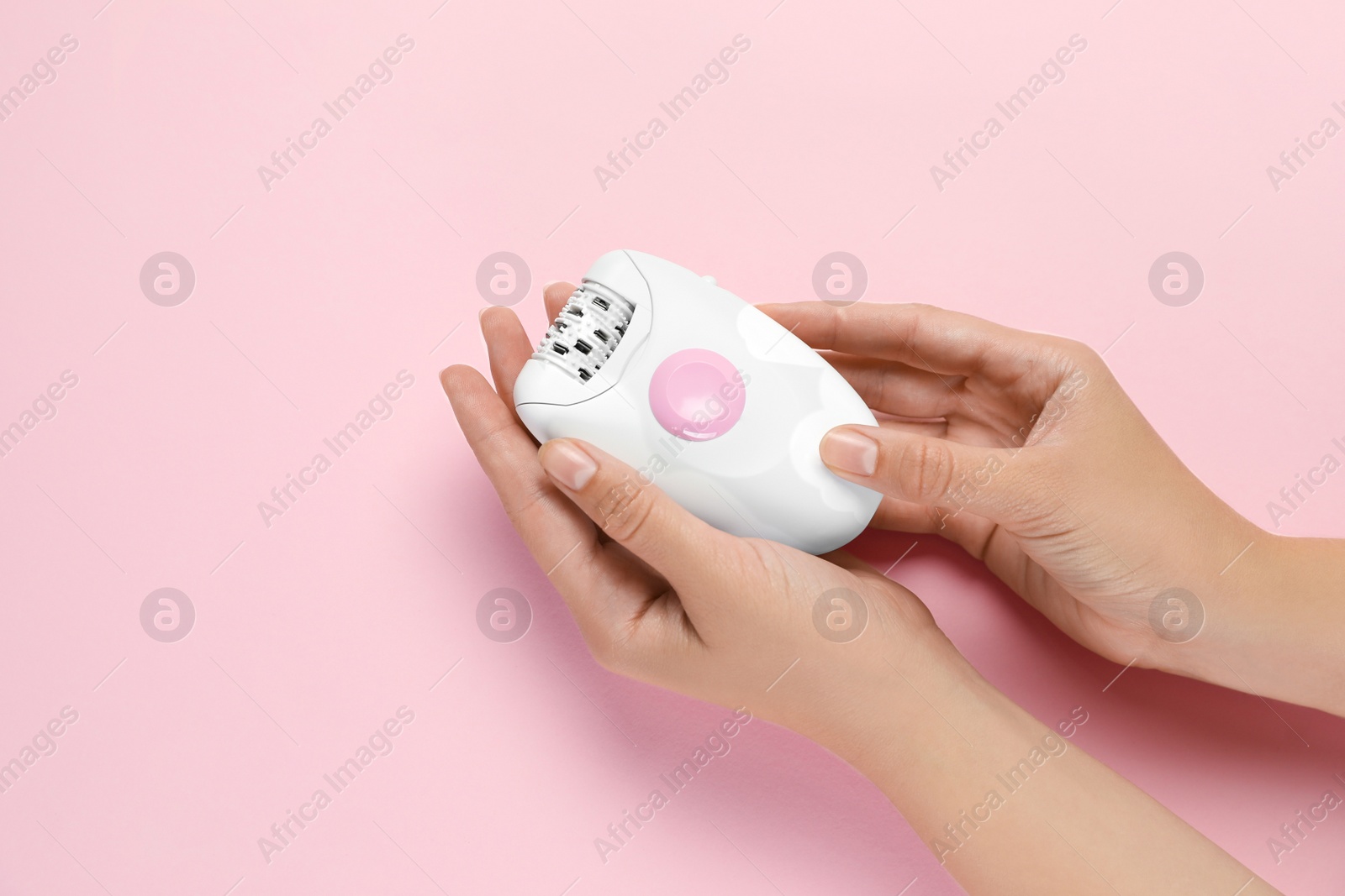 Photo of Woman holding modern epilator on pink background, top view