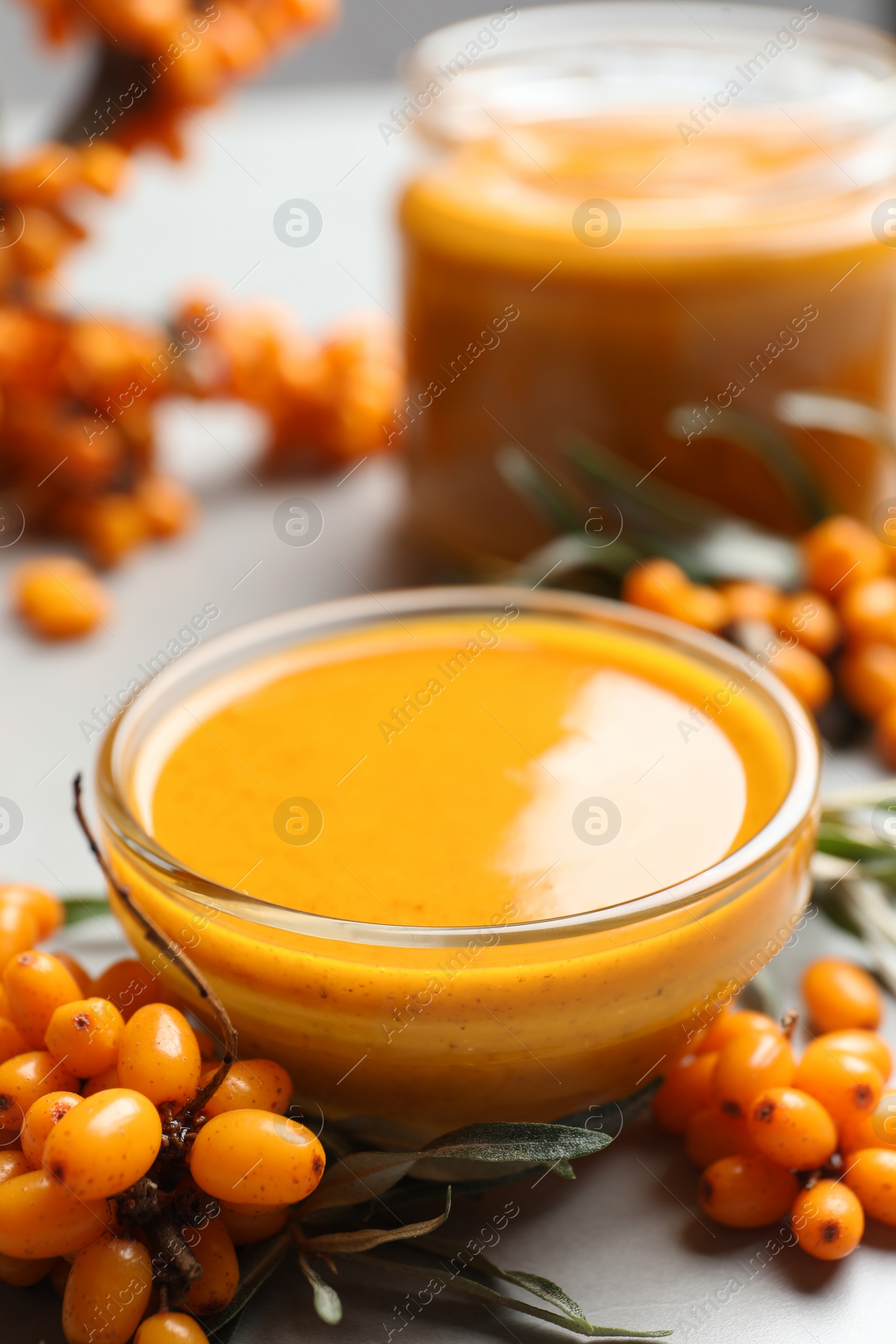 Photo of Delicious sea buckthorn jam and fresh berries on light grey table