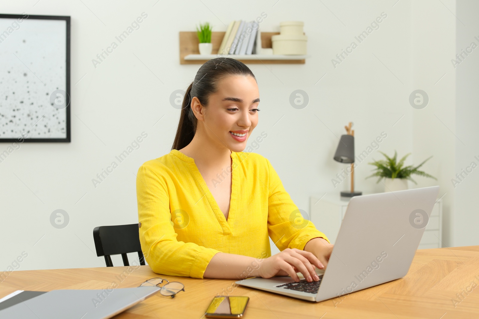 Photo of Home workplace. Woman working on laptop at wooden desk in room