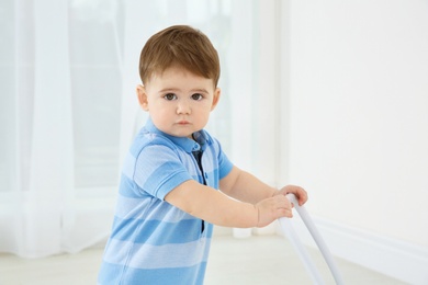 Cute baby playing with toy walker indoors