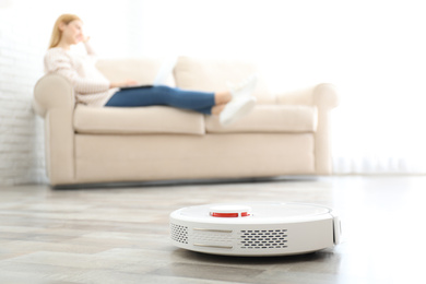 Photo of Woman resting while robotic vacuum cleaner doing her work at home