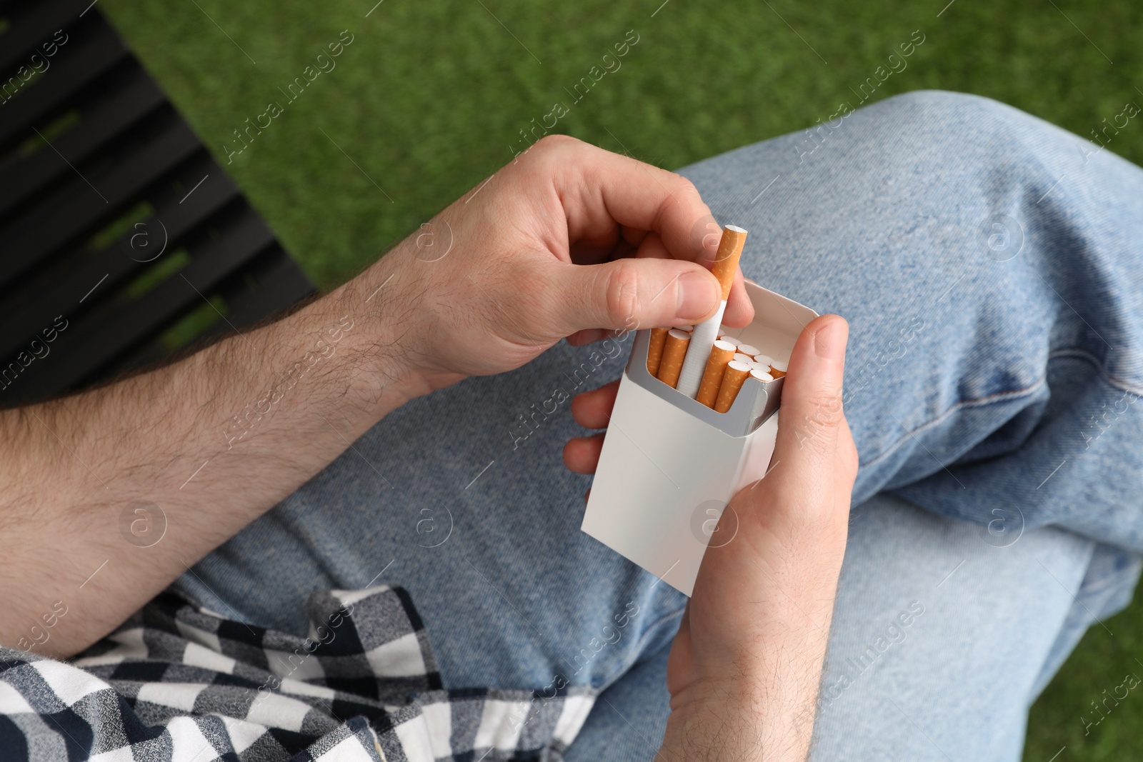 Photo of Man taking cigarette from pack outdoors, above view