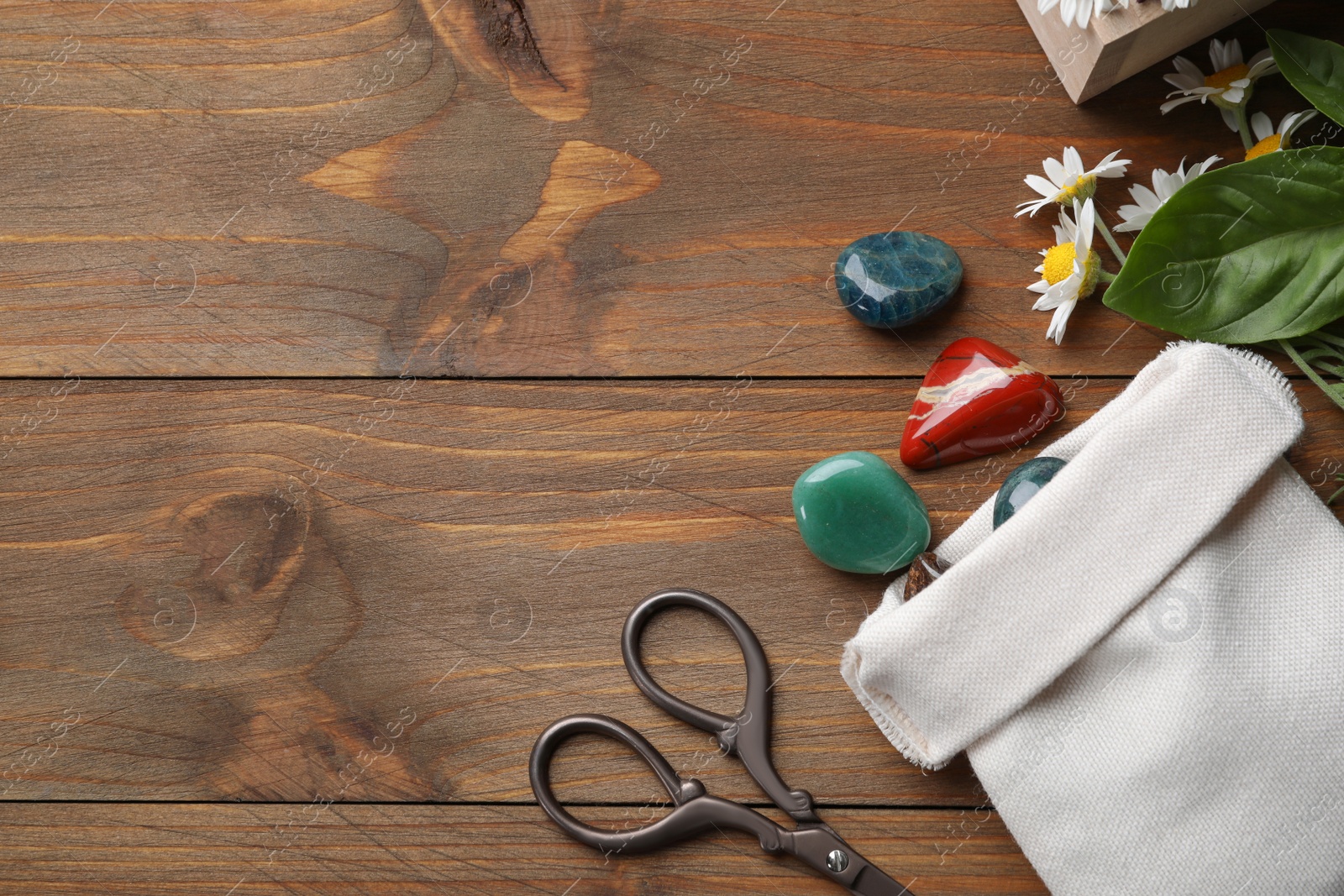 Photo of Flat lay composition with different gemstones and healing herbs on wooden table, space for text