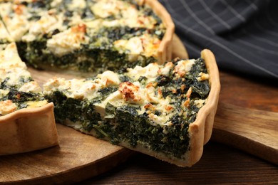 Delicious homemade spinach quiche on wooden board, closeup