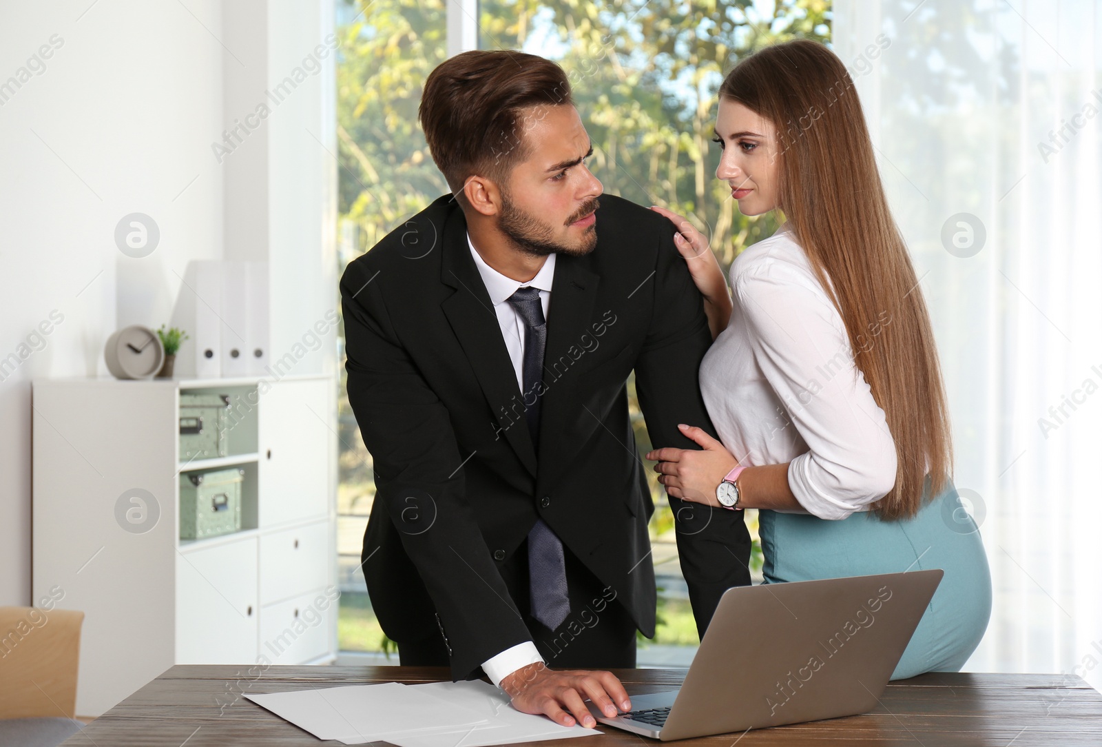 Photo of Woman molesting her male colleague in office. Sexual harassment at work