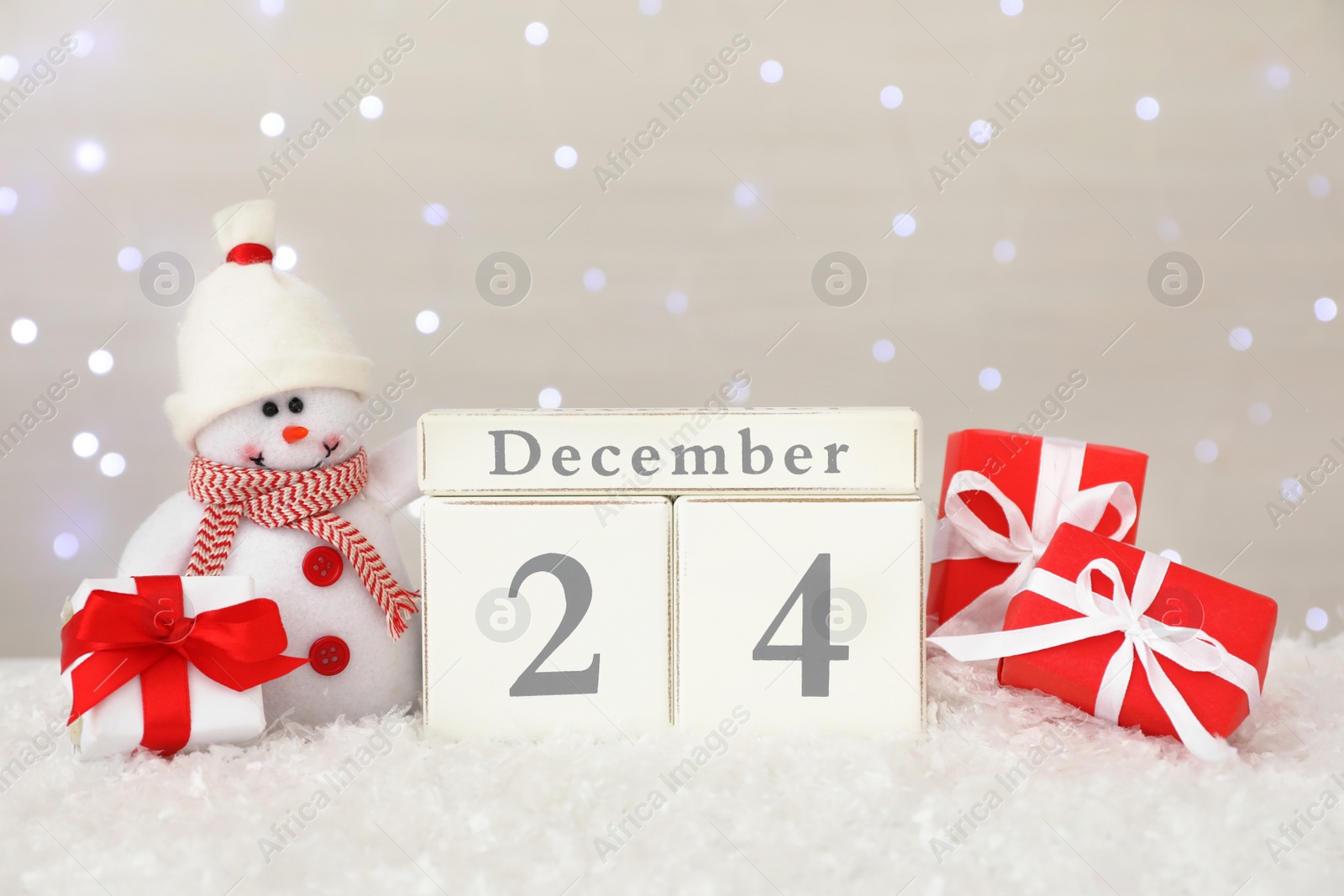 Photo of Christmas Eve - December 24. Wooden block calendar, cute toy snowman and gift boxes on artificial snow