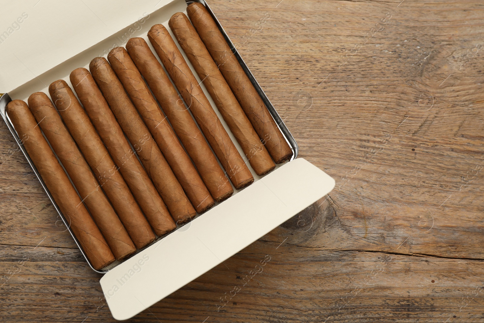 Photo of Humidor with cigars on wooden table, top view. Space for text