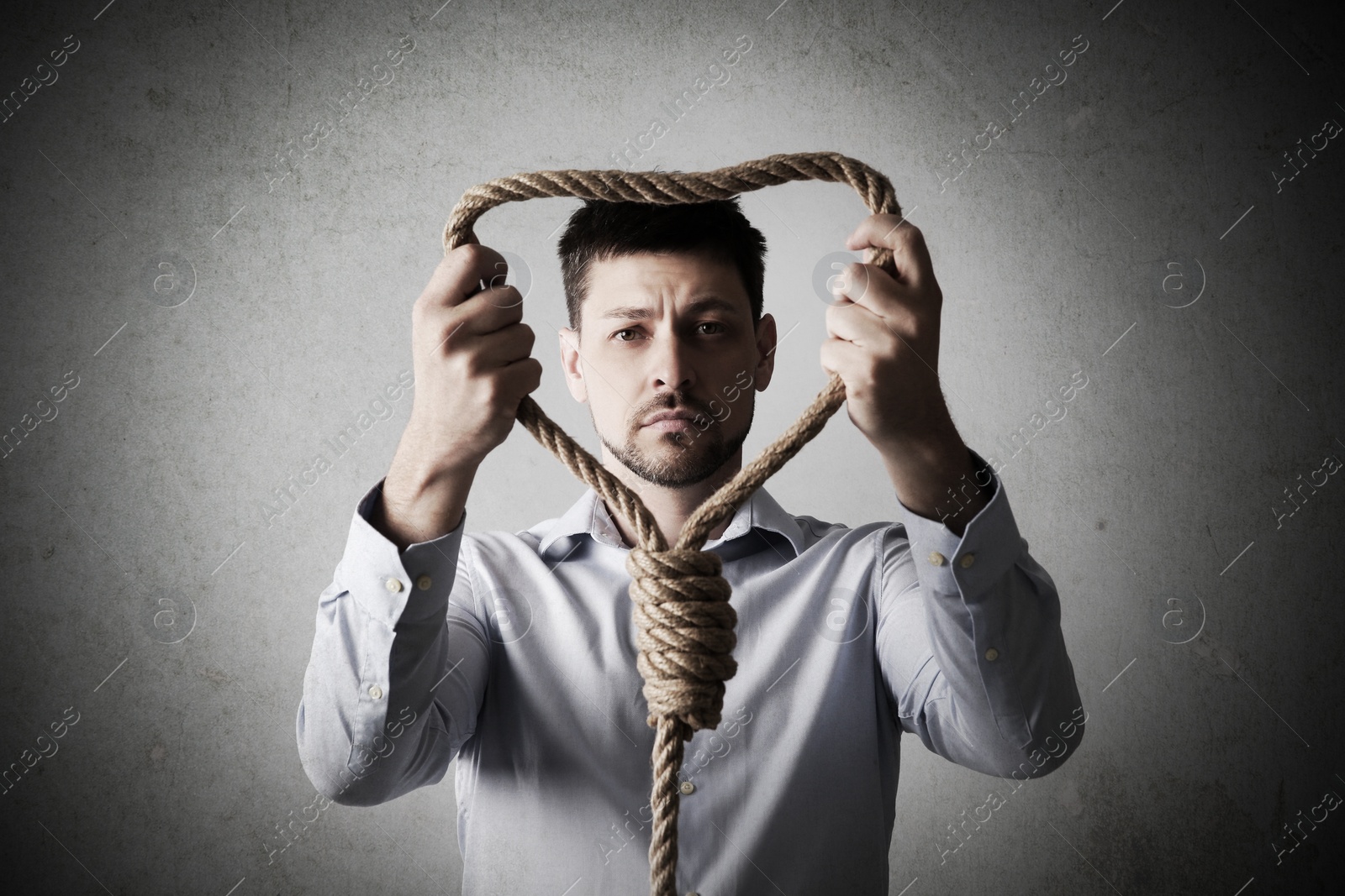 Image of Depressed man with rope noose on light background. Suicide concept