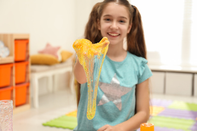 Photo of Preteen girl with slime in playroom, focus on hand