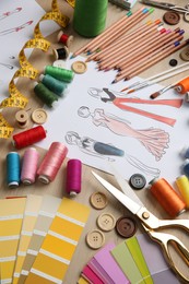 Photo of Sketch of fashion clothes and thread supplies at designer's workplace