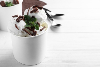 Yummy ice cream with chocolate served on white wooden table. Space for text