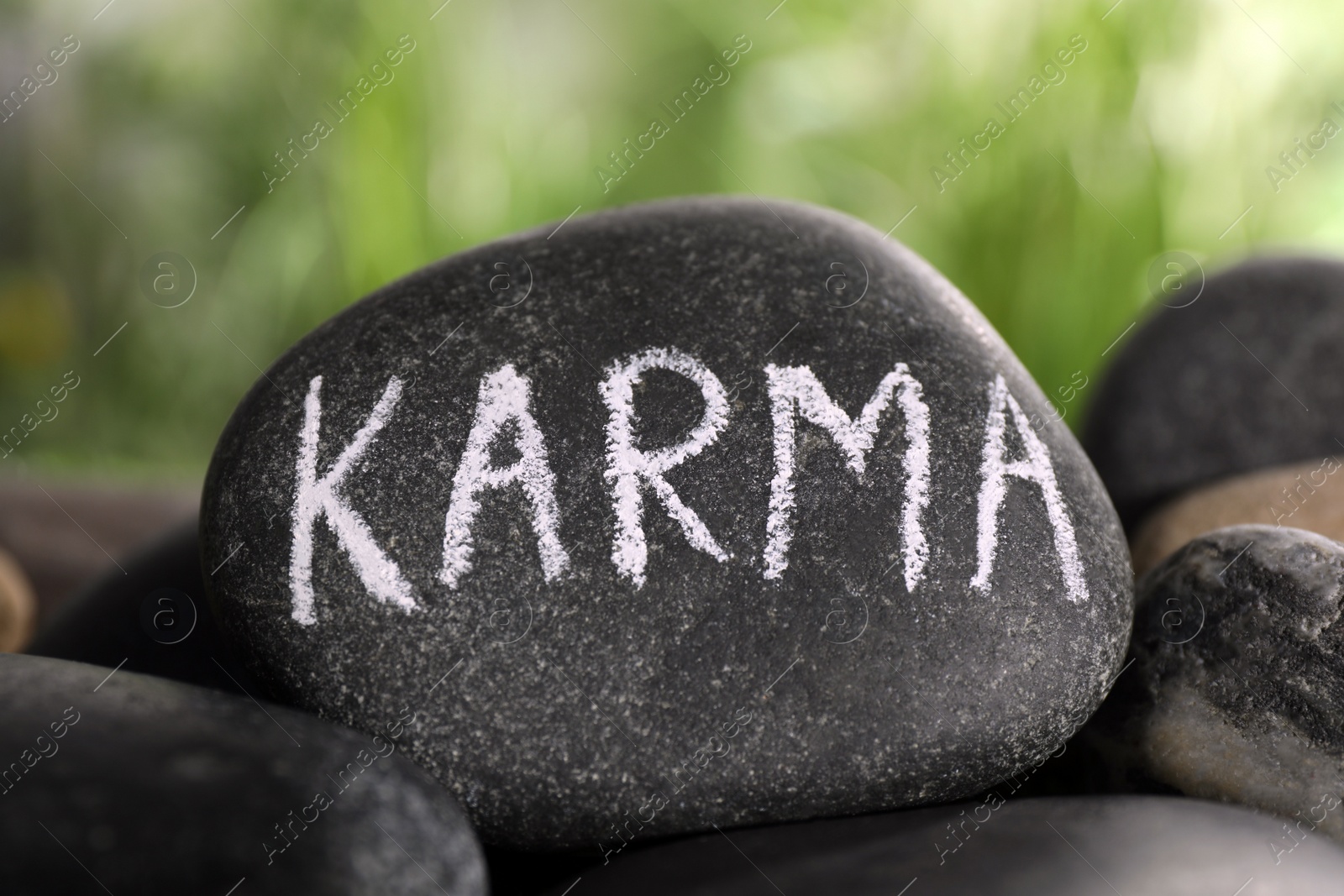Photo of Stone with word Karma on blurred background, closeup