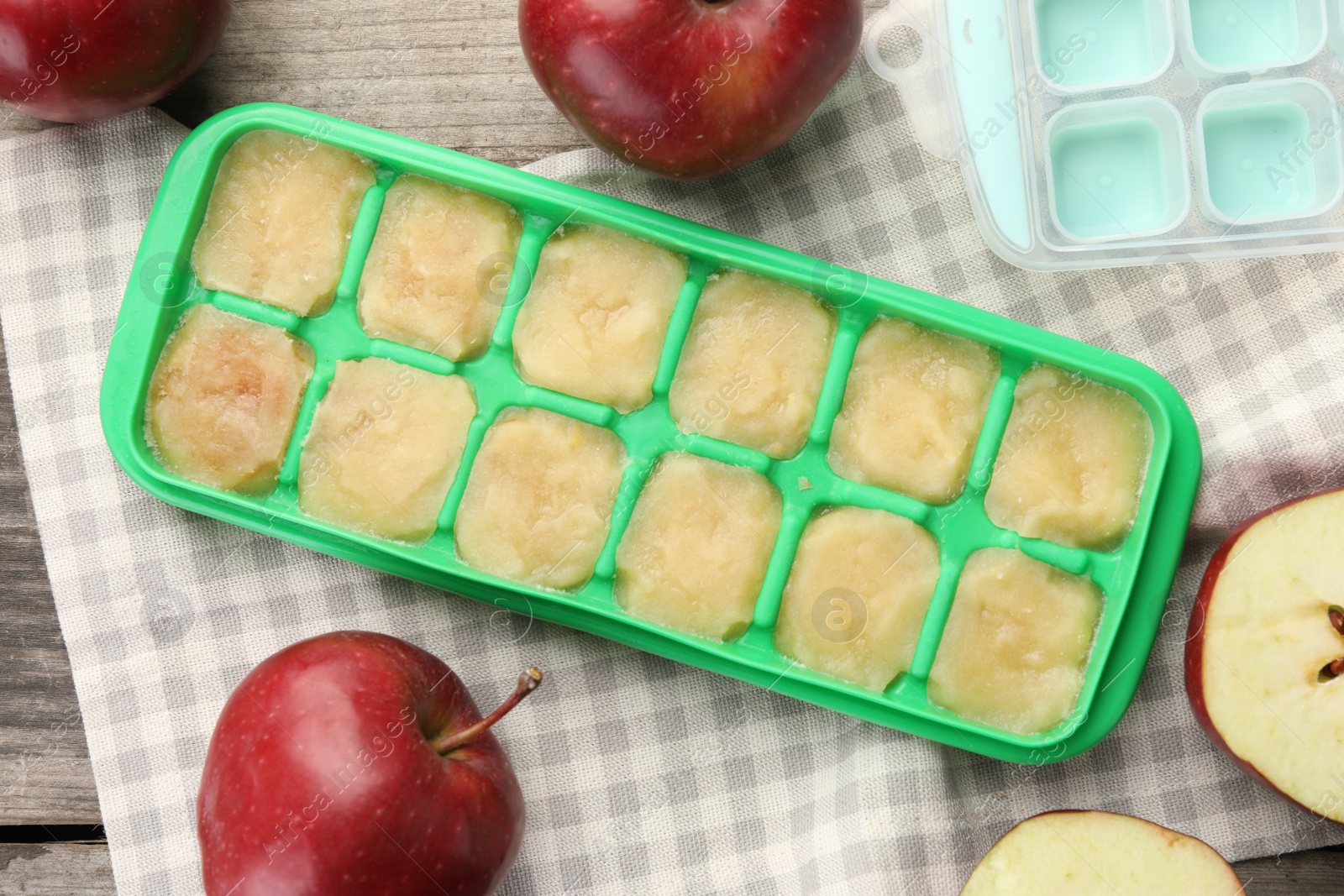 Photo of Apple puree in ice cube tray with ingredients on table, flat lay