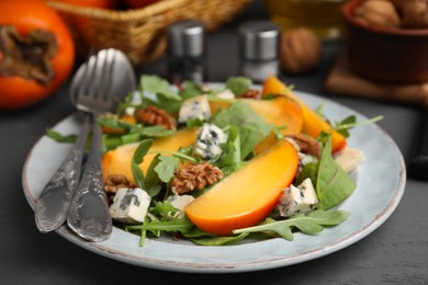 Tasty salad with persimmon, blue cheese and walnuts served on grey wooden table, closeup