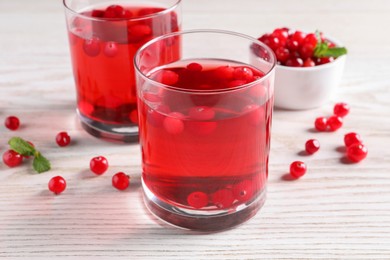 Tasty cranberry juice in glasses and fresh berries on white wooden table