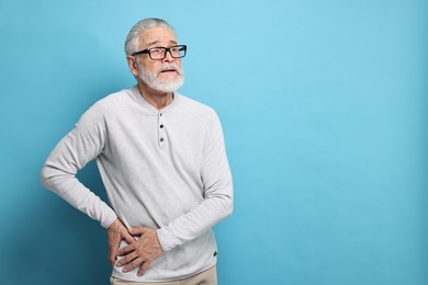 Photo of Arthritis symptoms. Man suffering from hip joint pain on light blue background, space for text