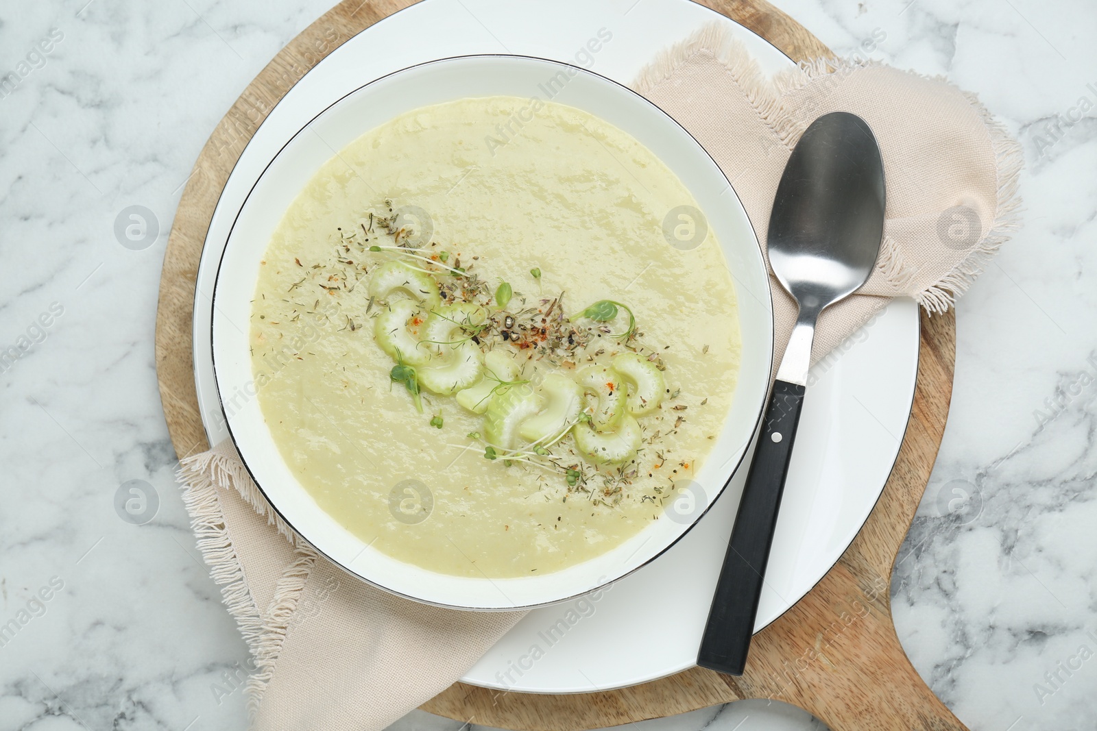 Photo of Delicious celery soup served on white marble table, top view