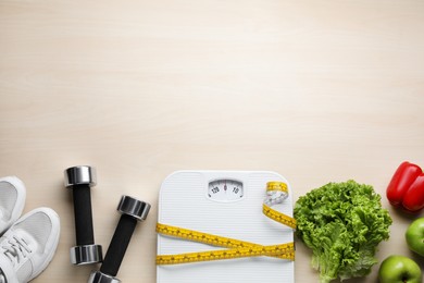 Photo of Flat lay composition with bathroom scale and measuring tape on wooden floor, space for text. Weight loss concept