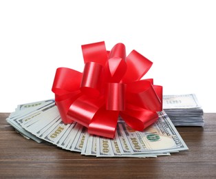 Photo of Dollar bills with red bow on wooden table against white background