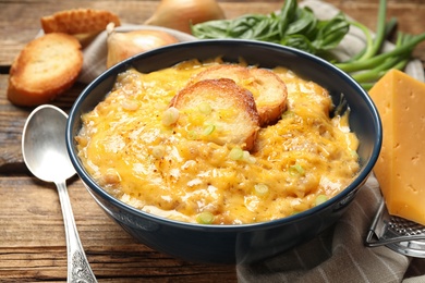 Tasty homemade French onion soup on wooden table, closeup