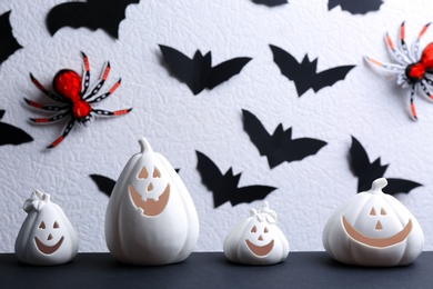 Photo of Composition with pumpkin shaped candle holders on black table against white background. Halloween decoration