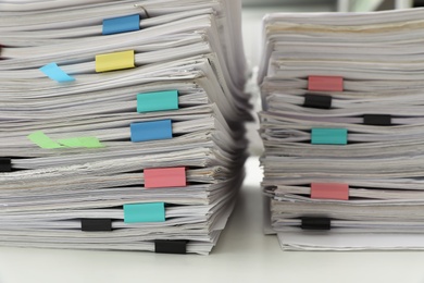 Stacks of documents with paper clips on office desk, closeup