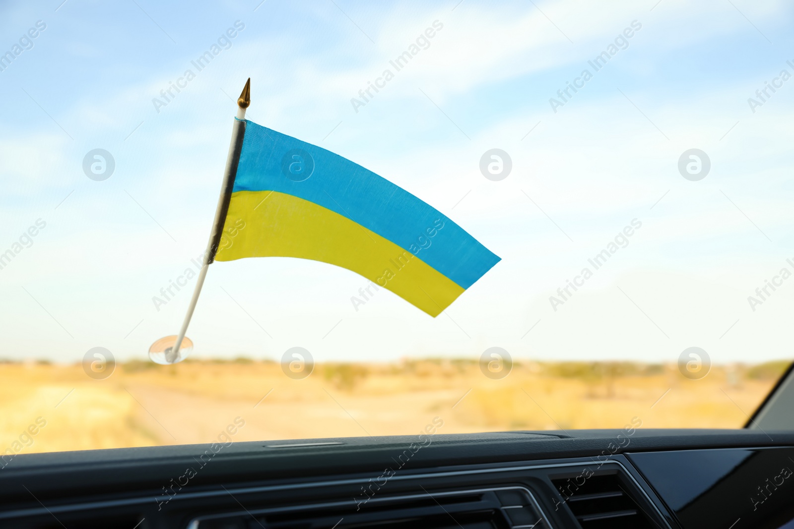 Photo of National flag of Ukraine on windshield inside car, closeup