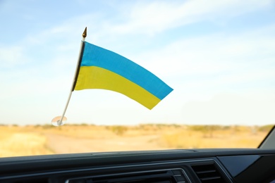 Photo of National flag of Ukraine on windshield inside car, closeup