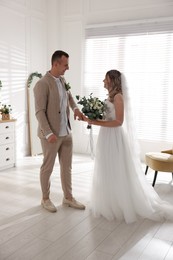 Happy groom and bride with bouquet indoors. Wedding day