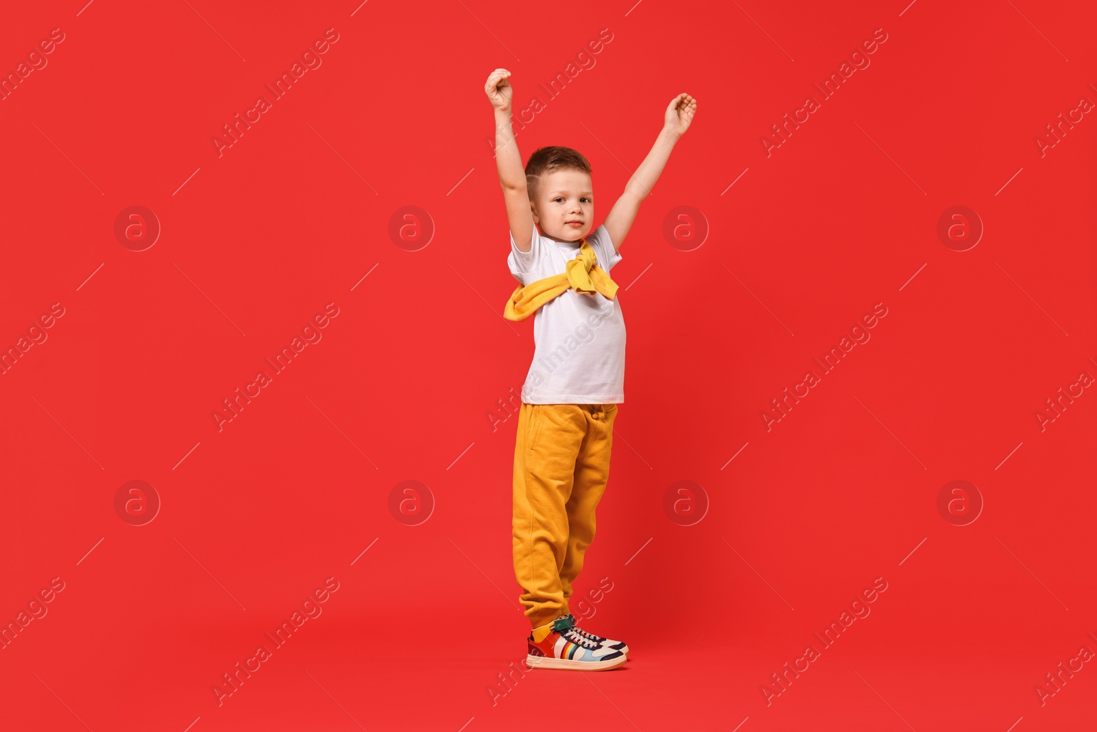 Photo of Happy little boy dancing on red background