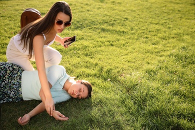 Photo of Woman checking pulse of unconscious person with heart attack in park