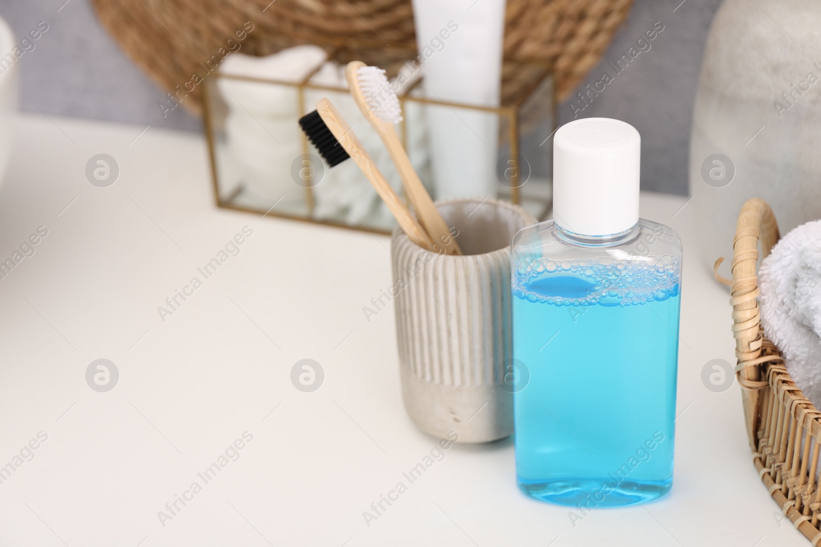 Photo of Bottle of mouthwash and toothbrushes on white table in bathroom, space for text