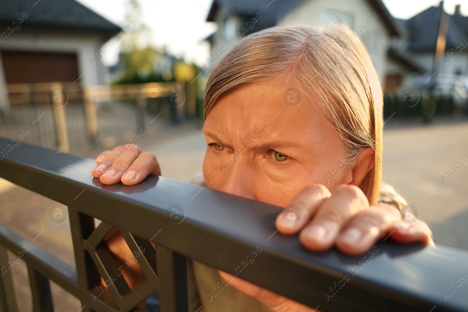 Photo of Concept of private life. Curious senior woman spying on neighbours over fence outdoors, closeup