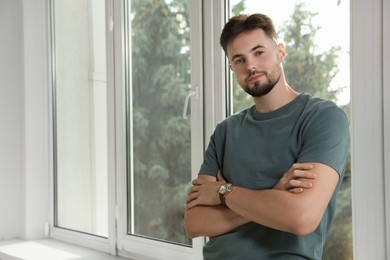 Photo of Portrait of handsome man near window indoors, space for text