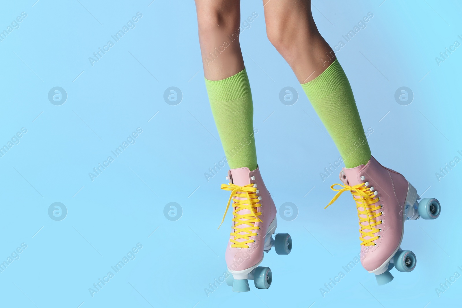 Photo of Woman with vintage roller skates on color background, closeup. Space for text