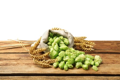 Overturned sack of hop flowers and wheat ears on wooden table against white background