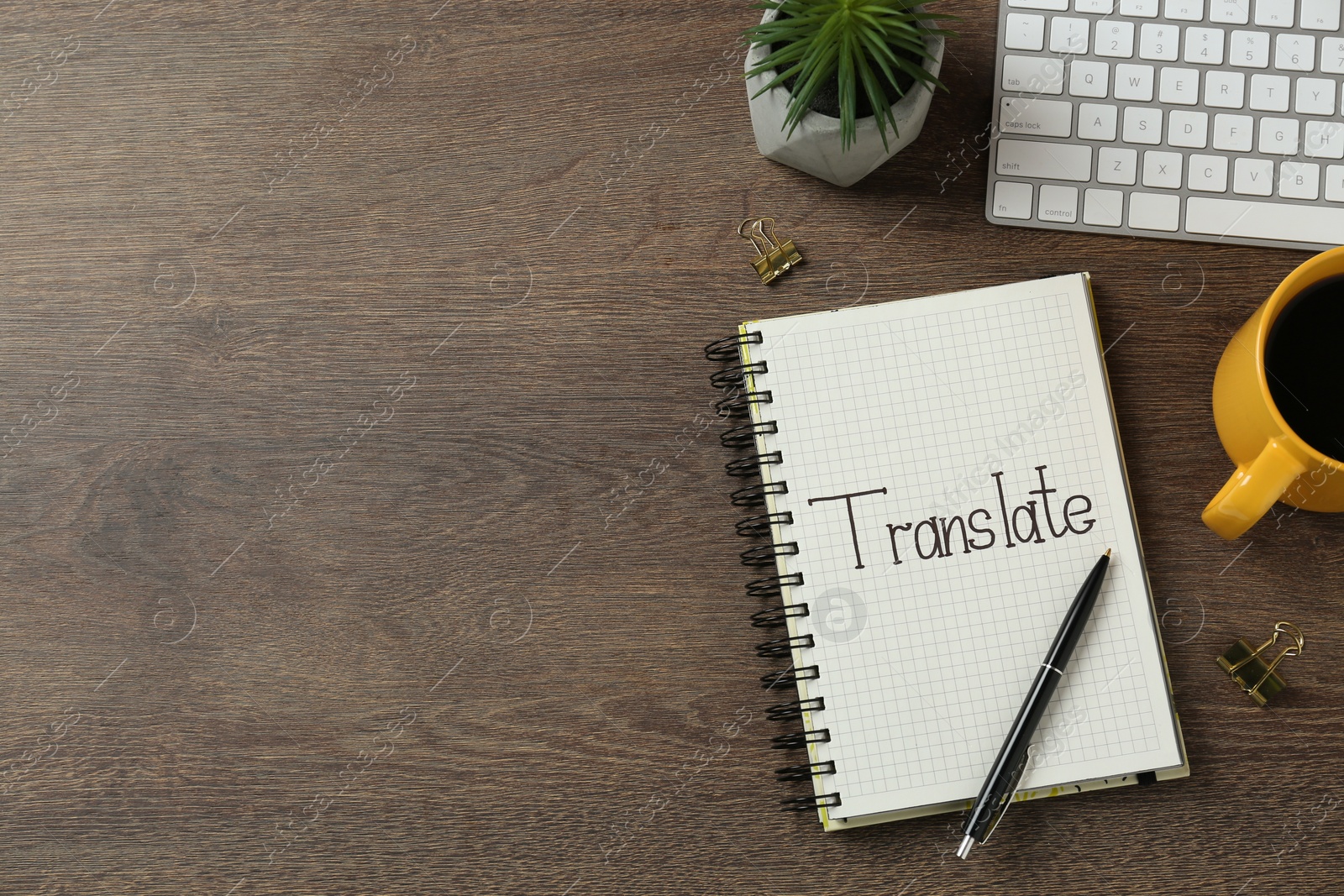 Photo of Word Translate written in notebook on wooden table, flat lay. Space for text